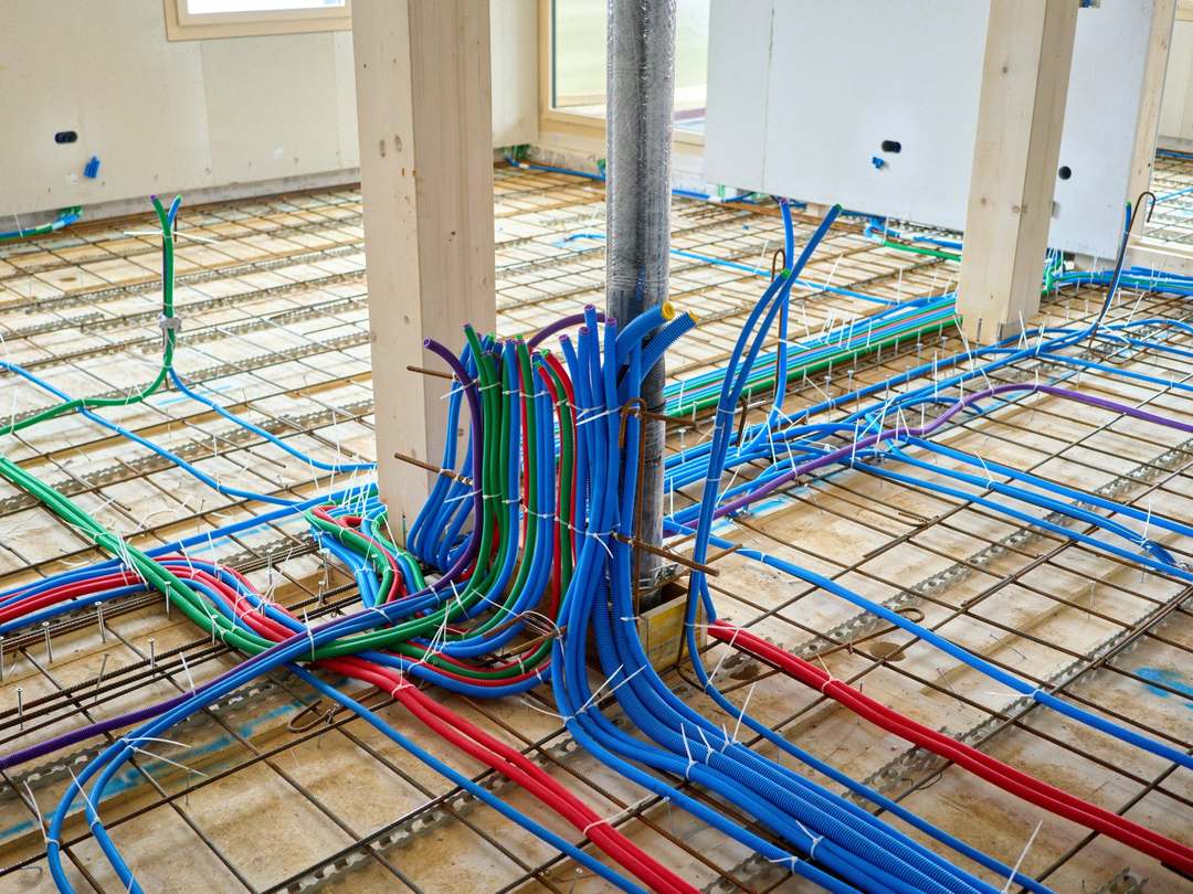 New heating and water pipework laid out neatly across a floor before it is covered