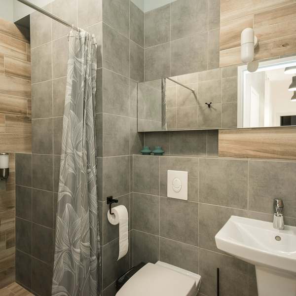 Small shower room with wood-effect and grey tiles, a pedestal basin and a wall-hung toilet