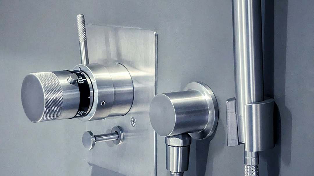 Brushed steel thermostatic shower valve and hand shower on a grey wall